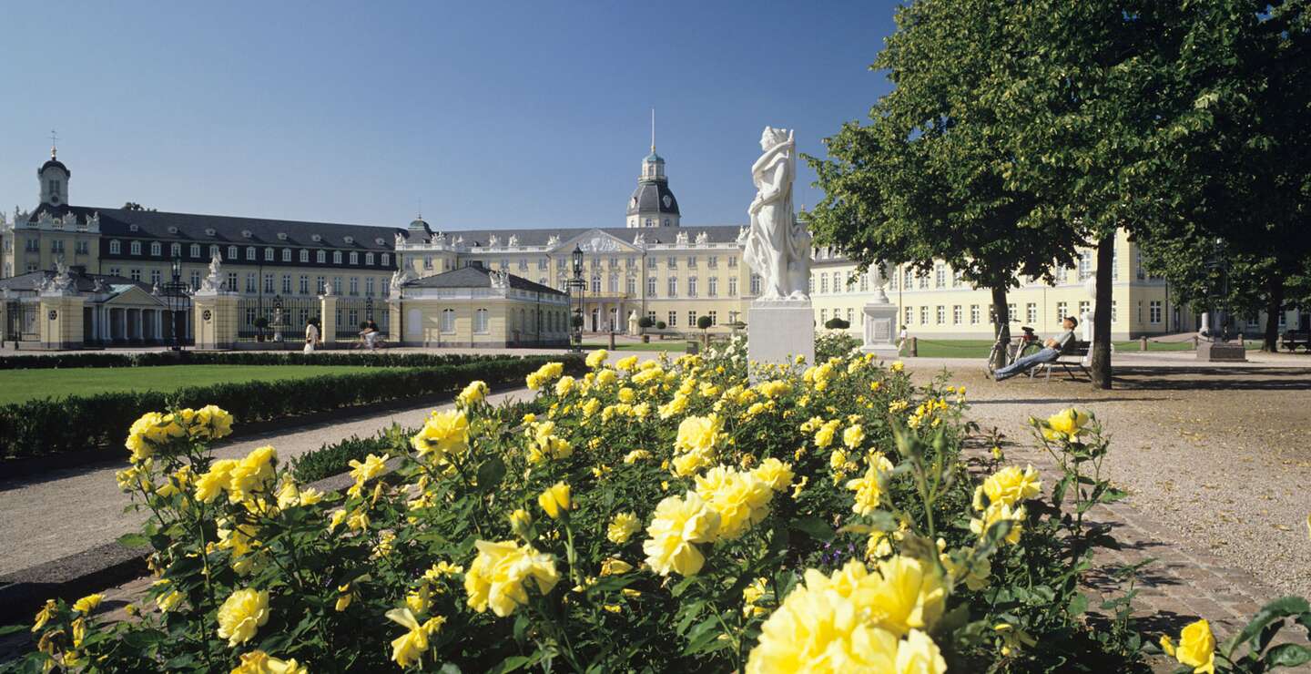 Schloss Karlsruhe mit gelben Rosen im Vordergrund und blauem Himmel | © Gettyimages.com/rotofrank