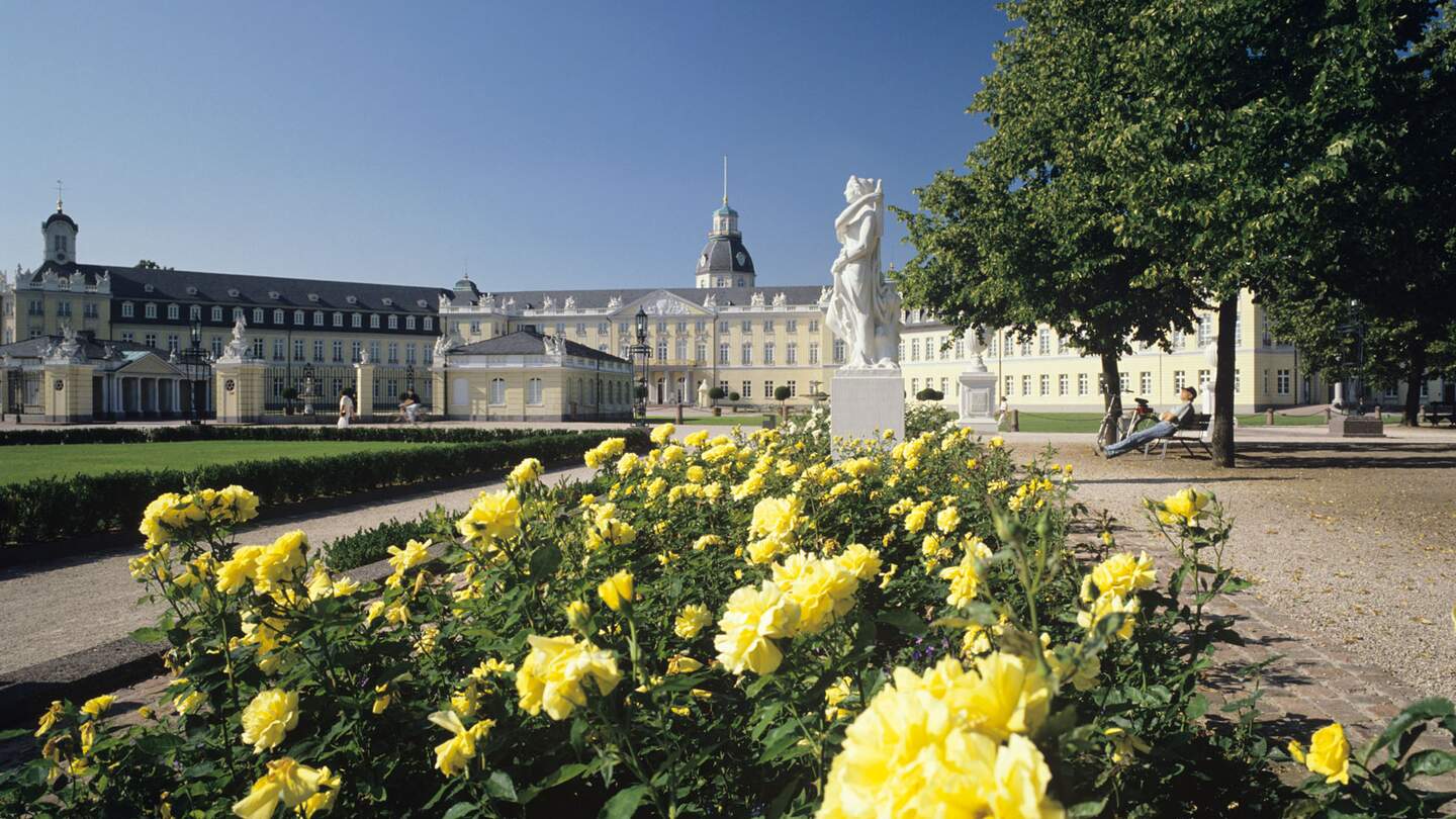 Schloss Karlsruhe mit gelben Rosen im Vordergrund und blauem Himmel | © Gettyimages.com/rotofrank