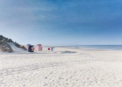 Strandkörbe auf der Insel Borkum mit weißem Sand und ein blauer Himmel | © Gettyimages.com/tobiasschwarz