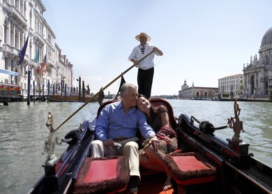 Glückliches Paar, das an einem sonnigen Tag in einer Gondel auf dem Canal Grande sitzt. | © Gettyimages.com/Getty Images