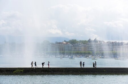 Menschen laufen unter Jet D'eau in Genf bei gutem wetter | © Gettyimages.com/omersukrugoksu