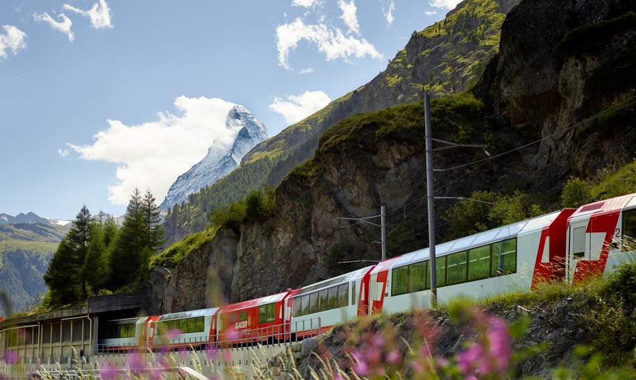 Der Glacier Express fährt durch Zermatt in der Schweiz im Frühling | © Glacier Express AG/Stefan Schlimpf