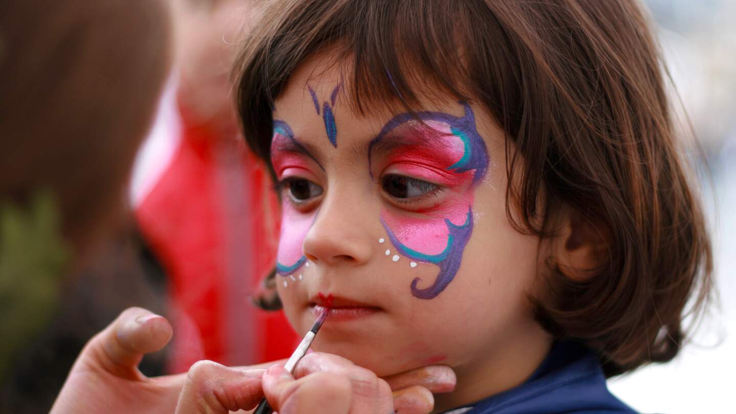 Kleines Mädchen bekommt einen Schmetterling ins Gesicht gemalt | © Gettyimages.com/belgium