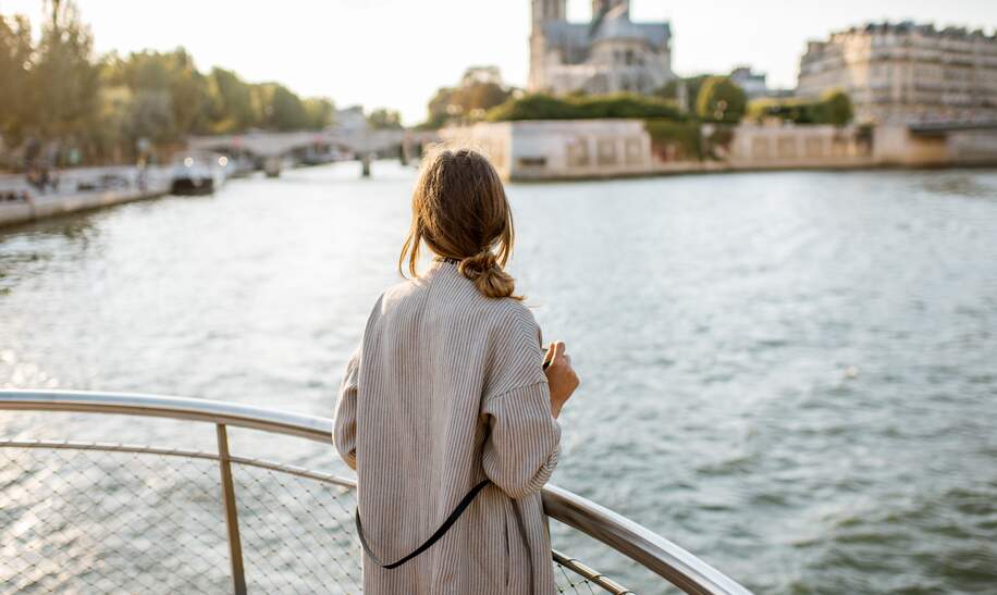 Frau genießt den Landschaftsblick auf die Stadt Paris vom Boot aus | © Gettyimages.com/RossHelen