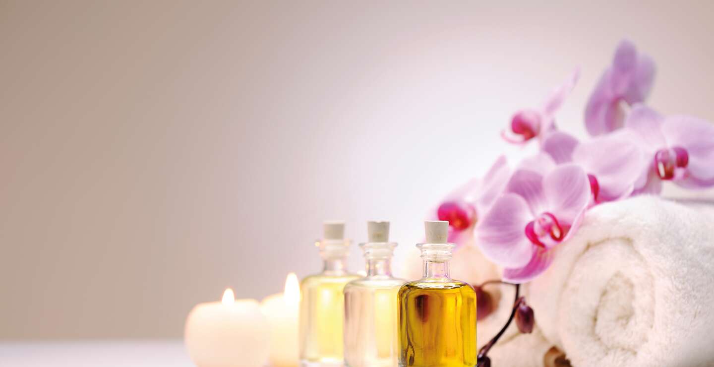 Handtücher, Orchideen, Kerzen und Öle vor weißem Hintergrund | © Gettyimages.com/Moncherie